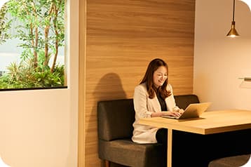 木目調の集中ブースでPC作業を行う女性スタッフ